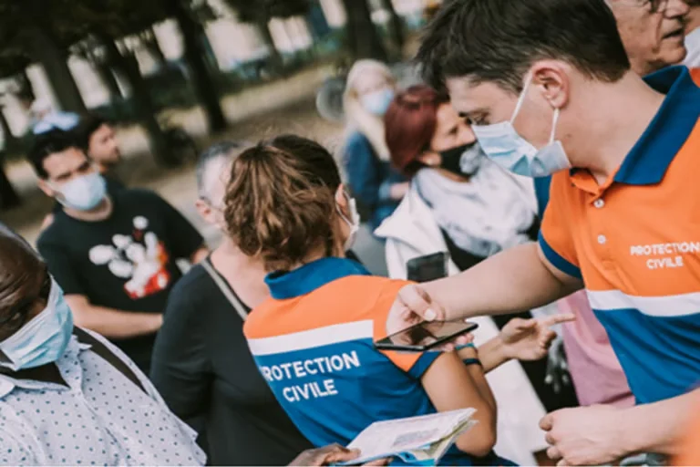 Volunteers in orange and blue vests guiding community members during an outreach session